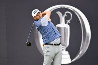 Daniel Brown strikes a tee shot in front of The Open banner