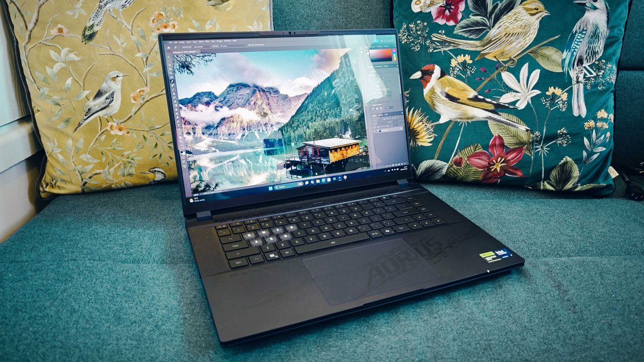 A Gigabyte Aorus Master 16 laptop on a green sofa
