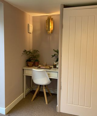 A backyard outbuilding with alcove home office setup complete with chair and desk decor and decorative wall sconce lighting