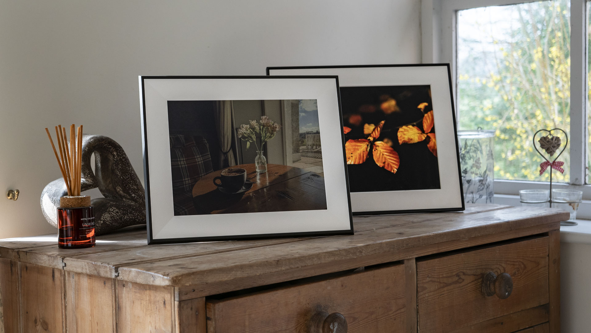 The Aura Ink 'E Ink' digital photo frame on a sideboard, alongside the Aura Walden frame