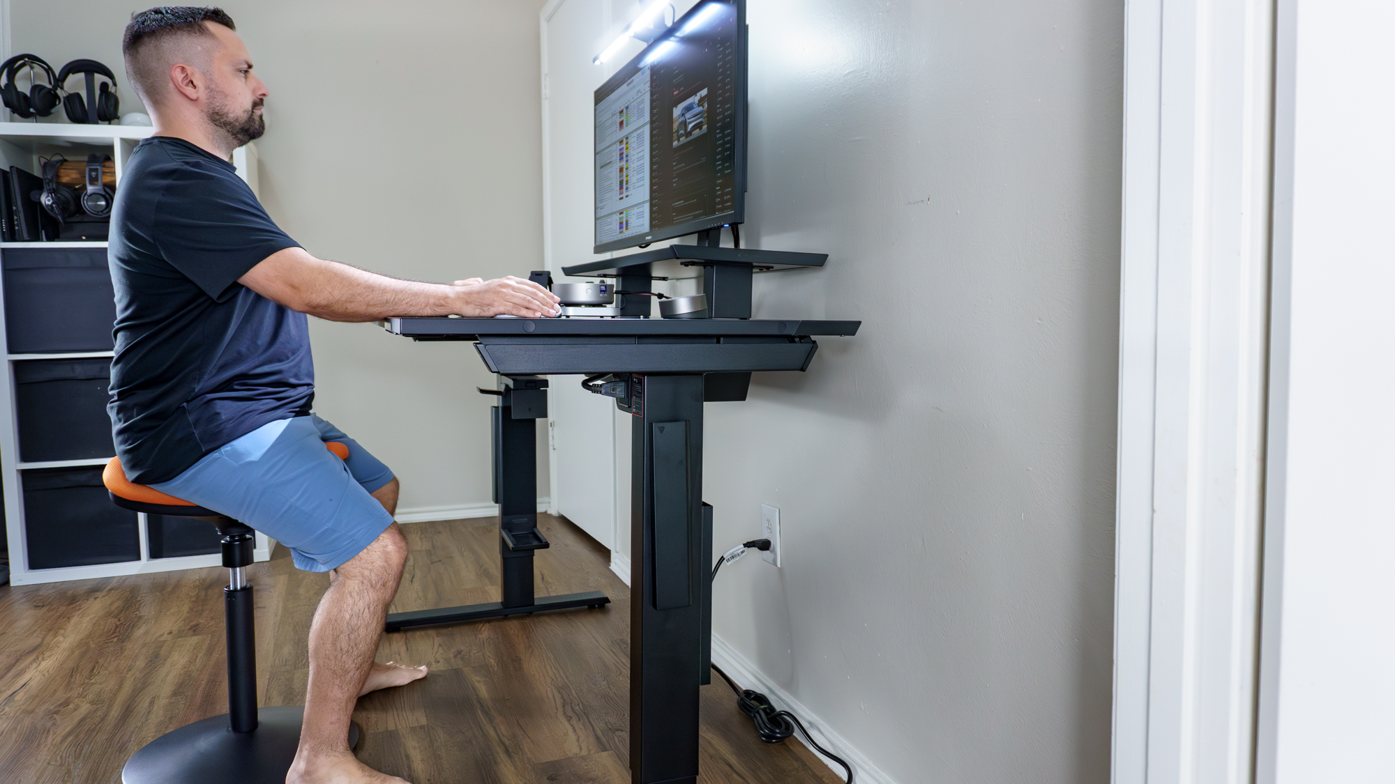 A person working at their desk sitting on a saddle stool