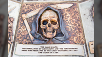a plaque with a human skull dressed as a grim reaper with text that reads "the black death. the population of monmouth and the surrounding areas was decimated by the great pestilence in 1349 and again in 1369".