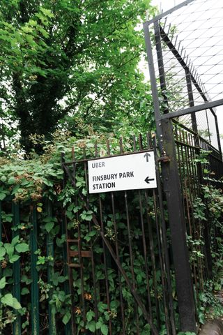 A sign showing directions on a fence in front of a tree