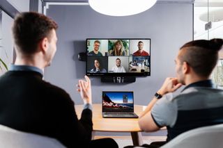 Two people join in a videoconference with six others using Airtame hybrid technology.