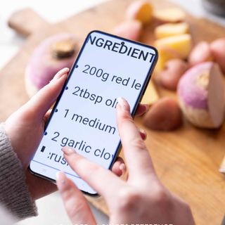 Hands holding a mobile phone with screen showing magnified recipe