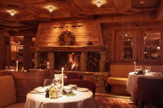 Wood-lined restaurant interior with fire place at Loulou Courchevel