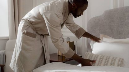 A man in a robe making the bed