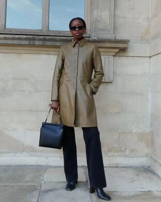 Woman wears khaki leather coat, black jeans, black boots