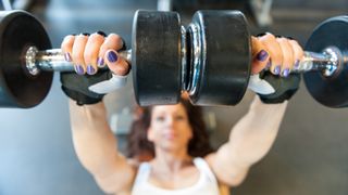 Woman performing a flat bench press with dumbbells