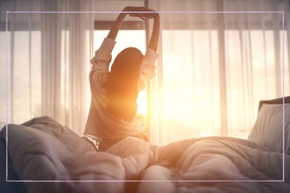 Woman stretching on the bed in early morning light