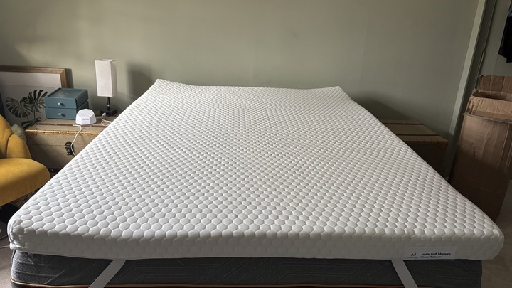The Helix Premium Memory Foam Mattress Topper with GlacioTex on a bed frame in a naturally lit bedroom.