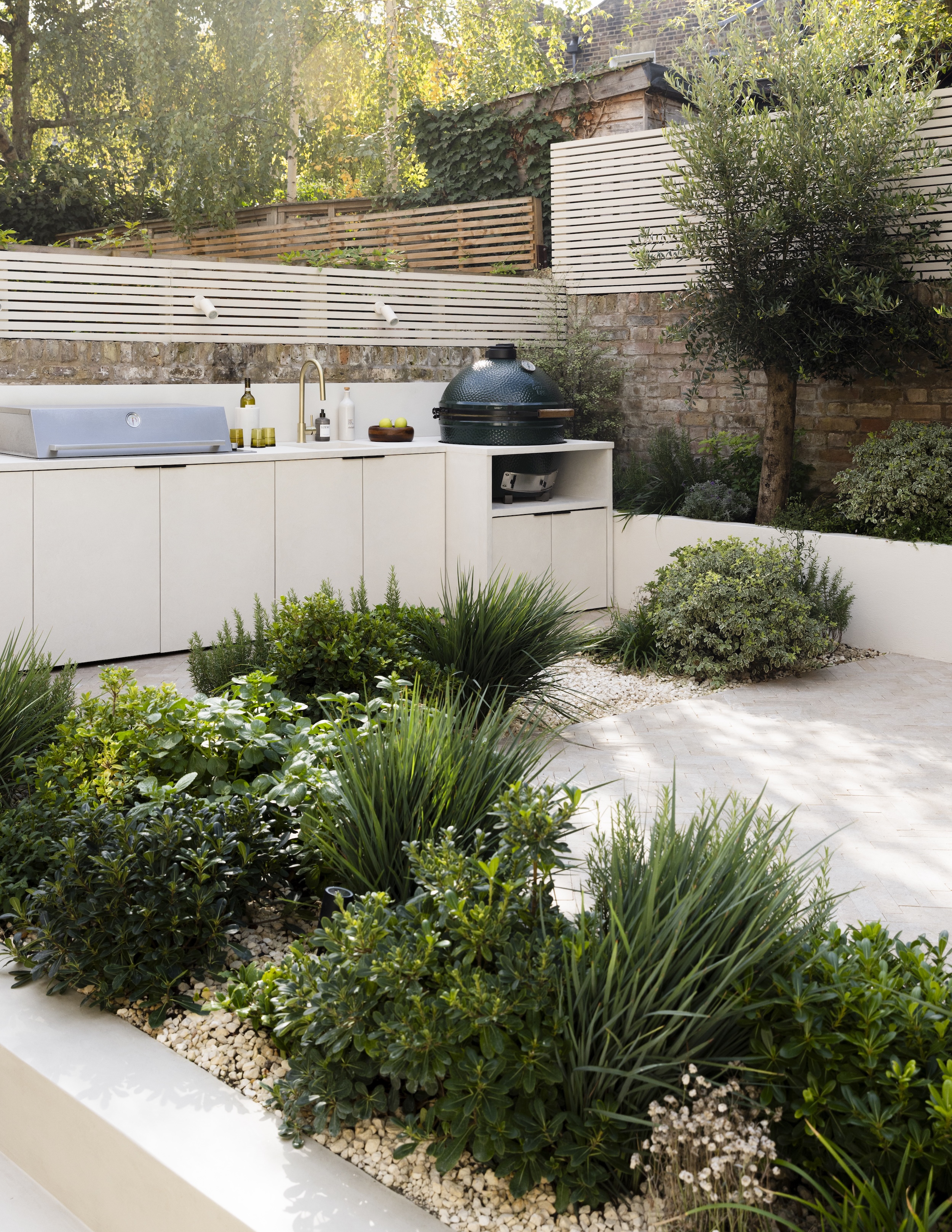 a mediterranean garden in london with an outdoor kitchen and olive trees