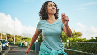 Woman walking along road on sunny day