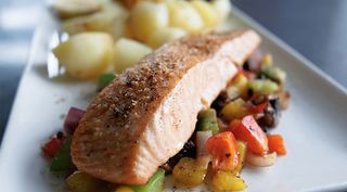 a fish dish that shows a cooked salmon on top of a bed of vegetables