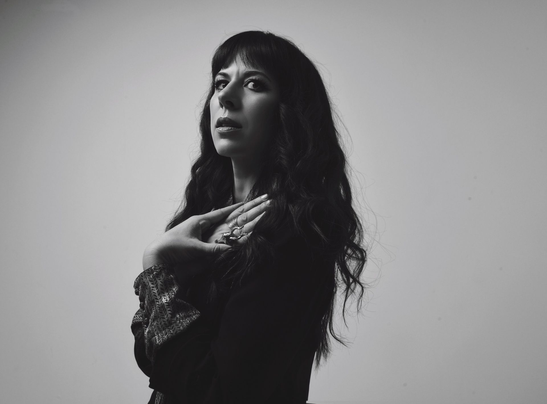 composer Missy Mazzoli poses in a black and white photo looking over her shoulder