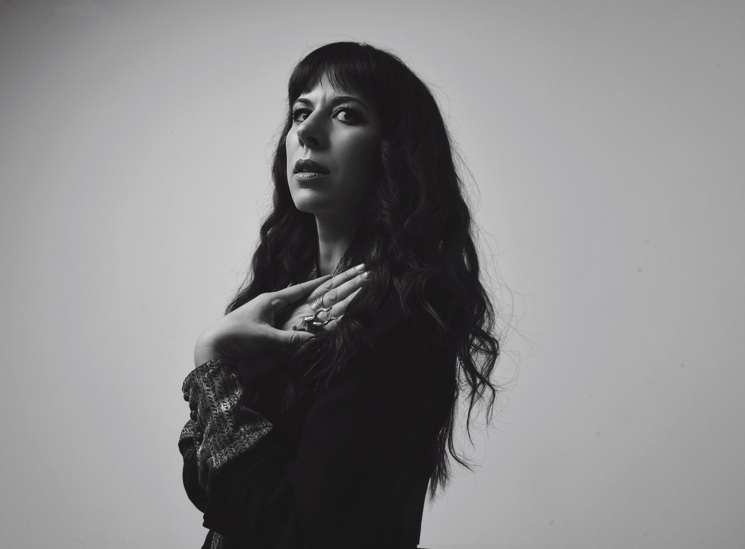 composer Missy Mazzoli poses in a black and white photo looking over her shoulder