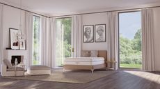 A White Saatva bedroom with large windows, wooden flooring, jute rug, large artworks above the Santorini bedframe, and a white mantelpiece with artworks and cream seating.
