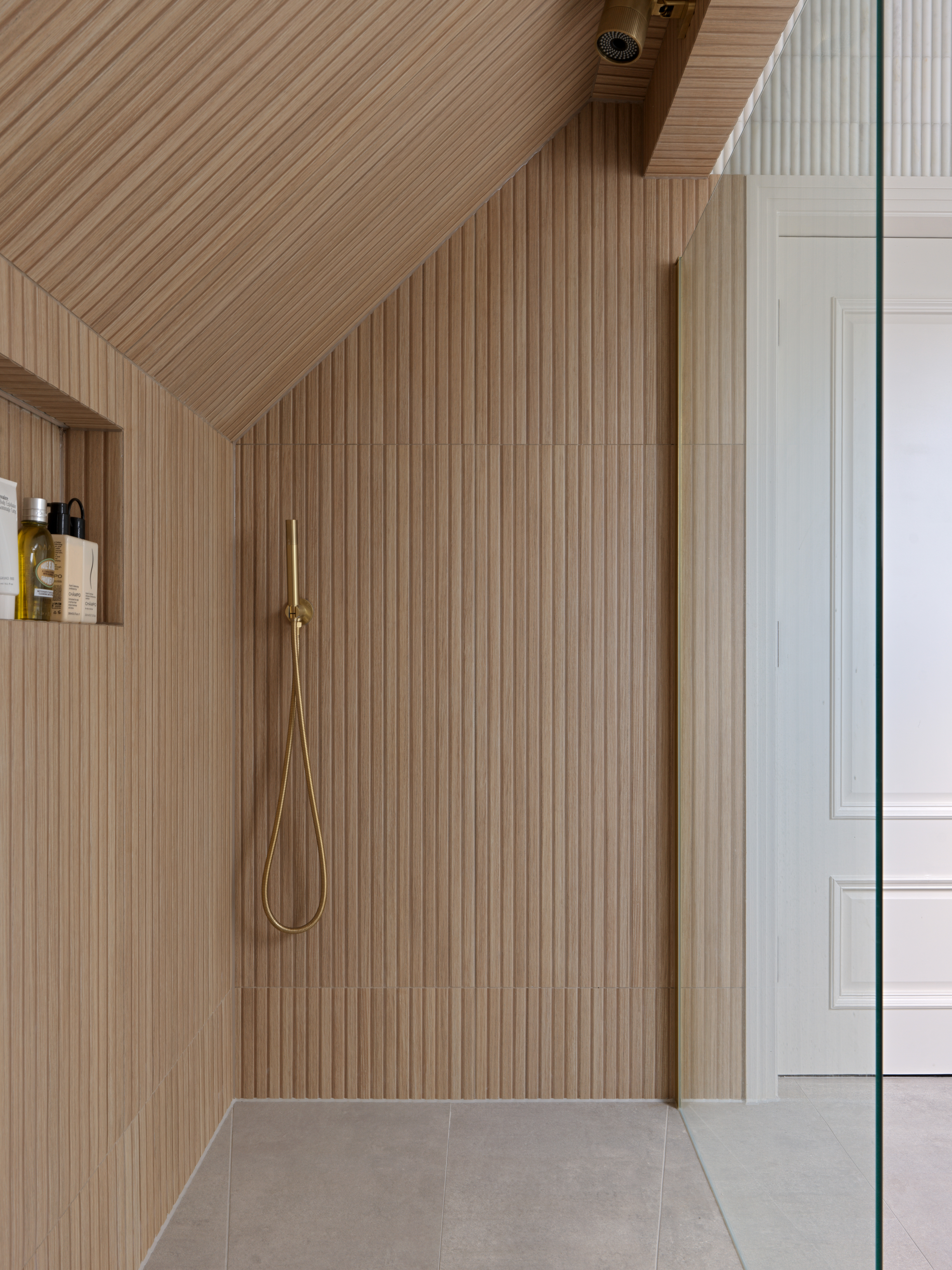 timber tiled wet room with gold hardware in a loft conversion bathroom