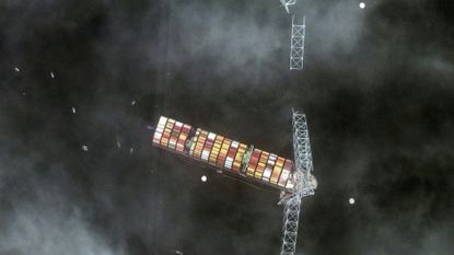 Aerial photo of a large cargo vessel as it crashes into the Francis Scott Key Bridge in Baltimore, Maryland, prompting its collapse.