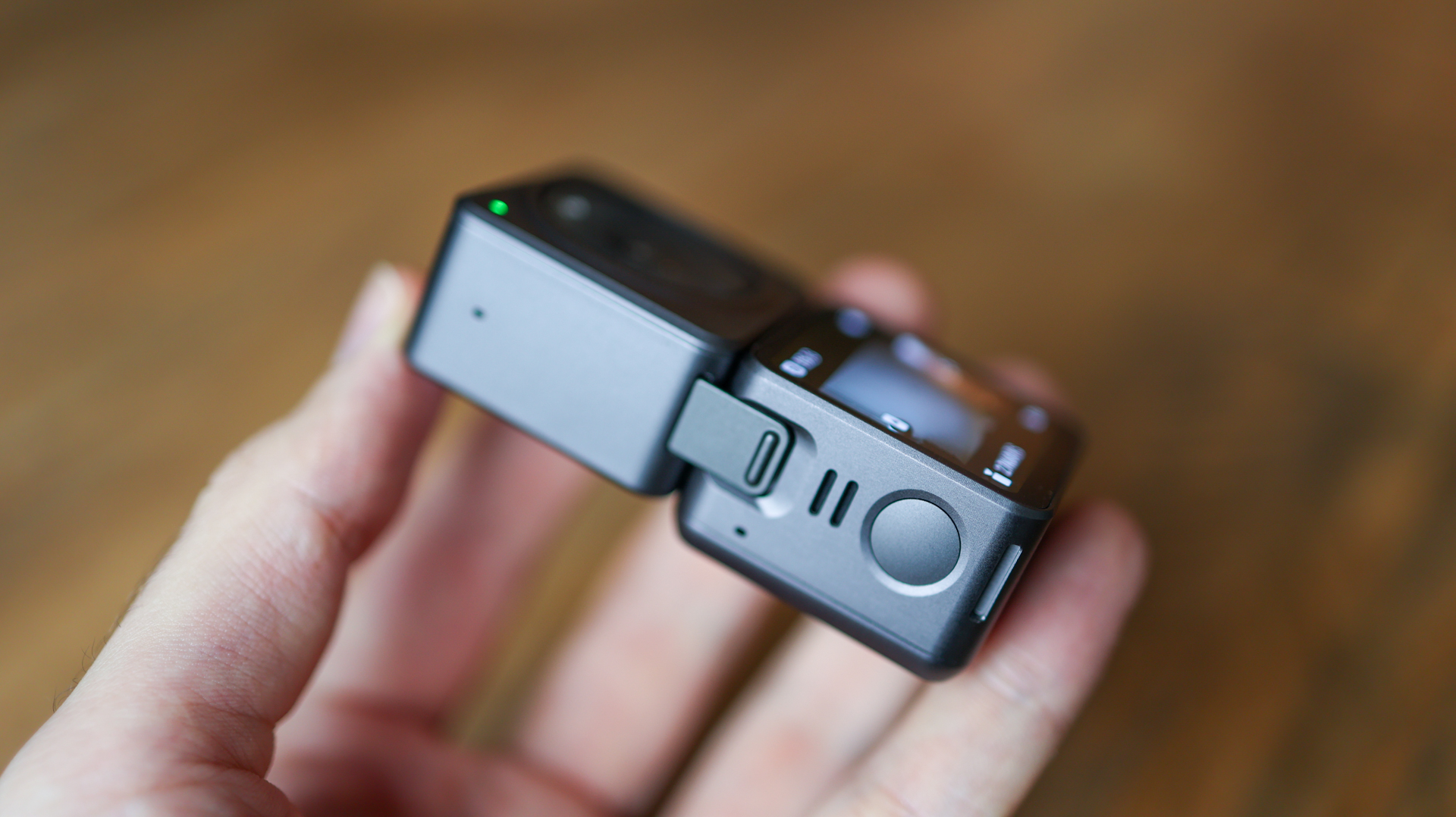 A hand holding the DJI Action 2 action camera showing its hinge