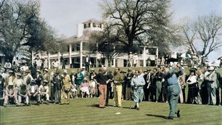 Bobby Jones plays his tee shot on the first hole while Tommy Armour, Walter Hagen and Gene Sarazen watch on the tee, alongside a gallery of patrons in front of the clubhouse during the 1935 Masters. Why is The Masters A Major?