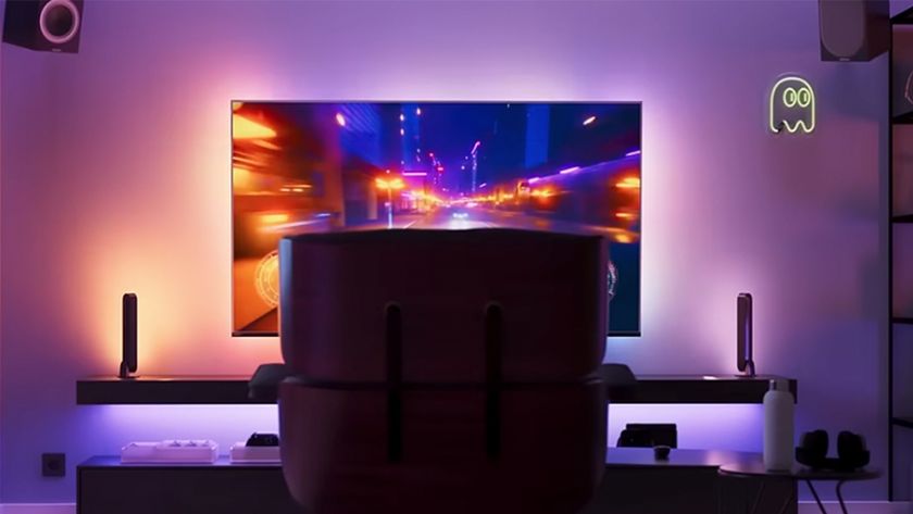 A TV set up with Philips Hue Sync Box with a chair in front of it. 