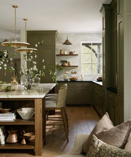 an L-shaped kitchen with dark olive green cabinets and a wooden island