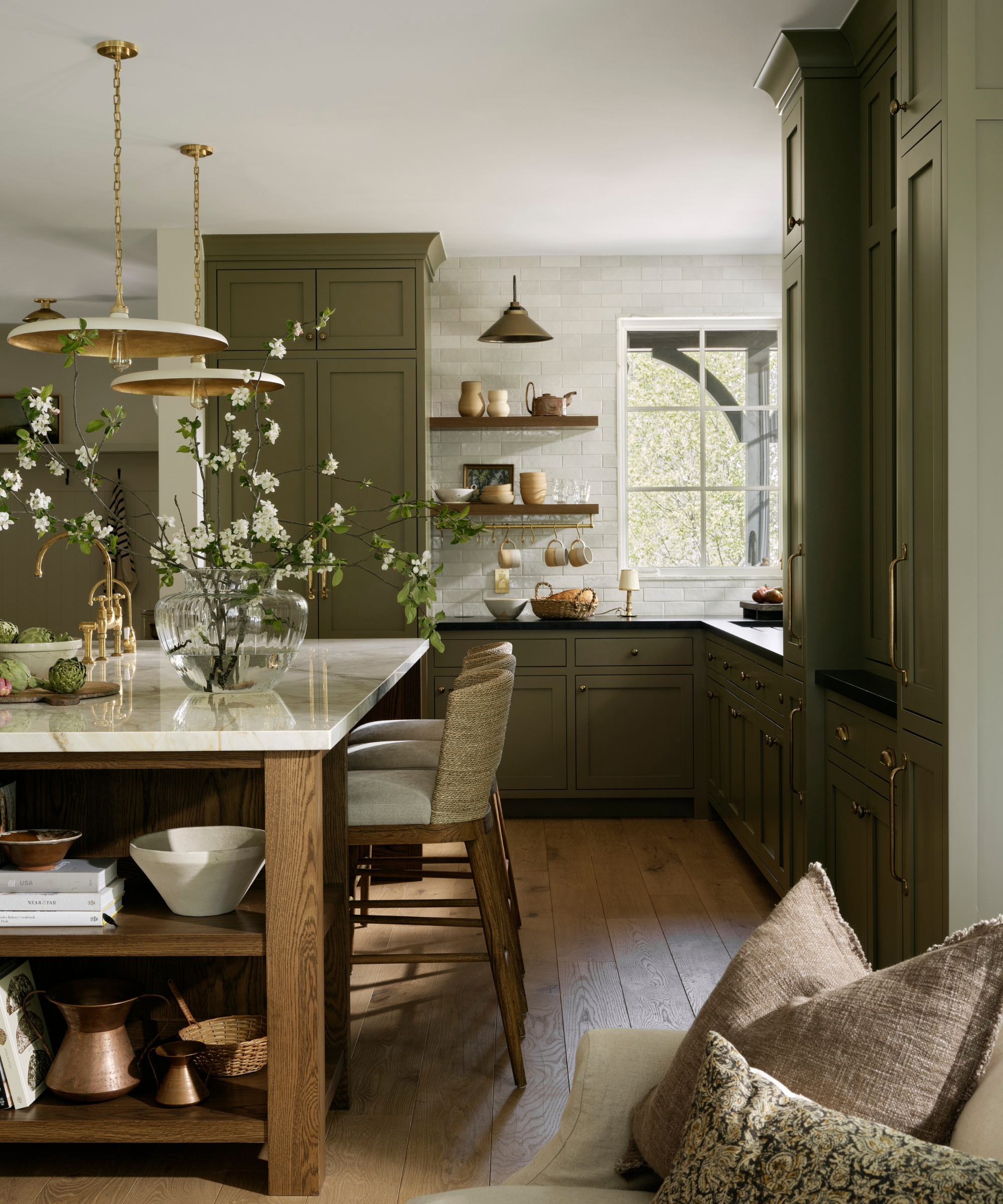 an L-shaped kitchen with dark olive green cabinets and a wooden island