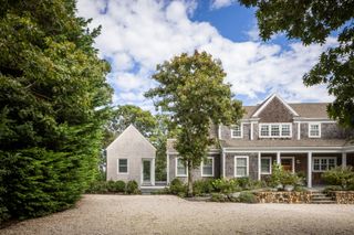 cape cod house exterior with pebble driveway and shed