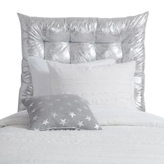 A silver headboard with white bedding
