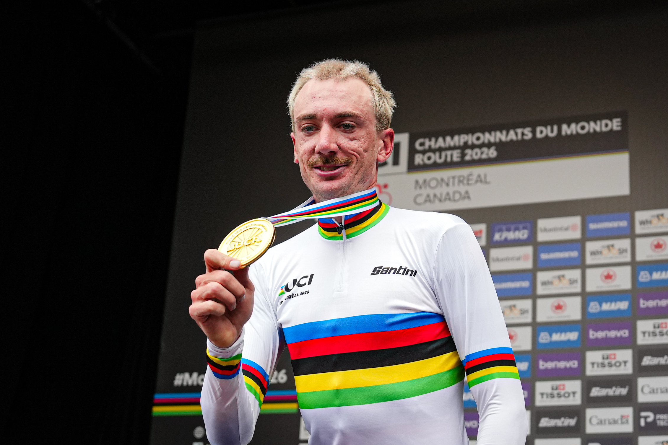 Brandon McNulty holding a gold medal and wearing a rainbow jersey