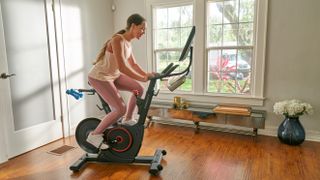 Athletic woman riding an Echelon Smart Connect Bike EX-5s in a living room