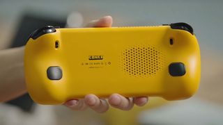 A hand holding the AYANEO KONKR Pocket FIT up so the back side is visible.