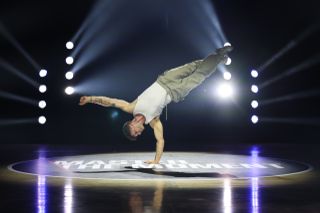 Canon EOS R5 Mark II sample image: a breakdancer dancing on a wooden floor, backlit with laser lighting