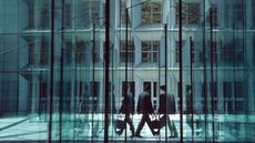 Man walking between large glass walls and doors