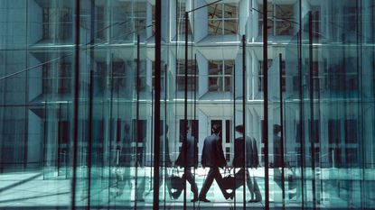 Man walking between large glass walls and doors