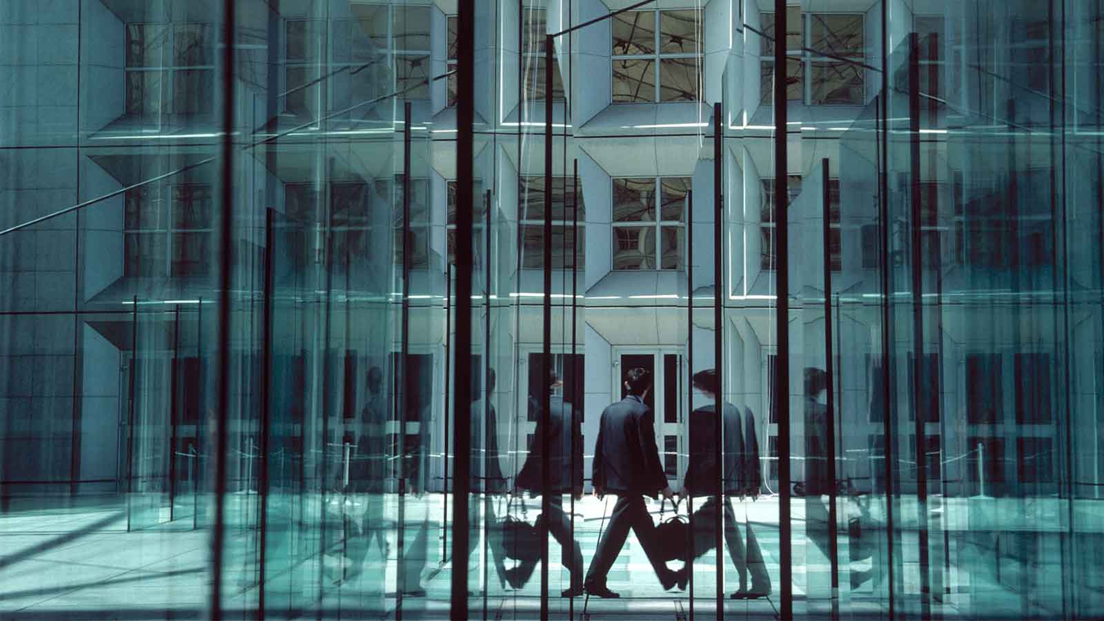 Man walking between large glass walls and doors