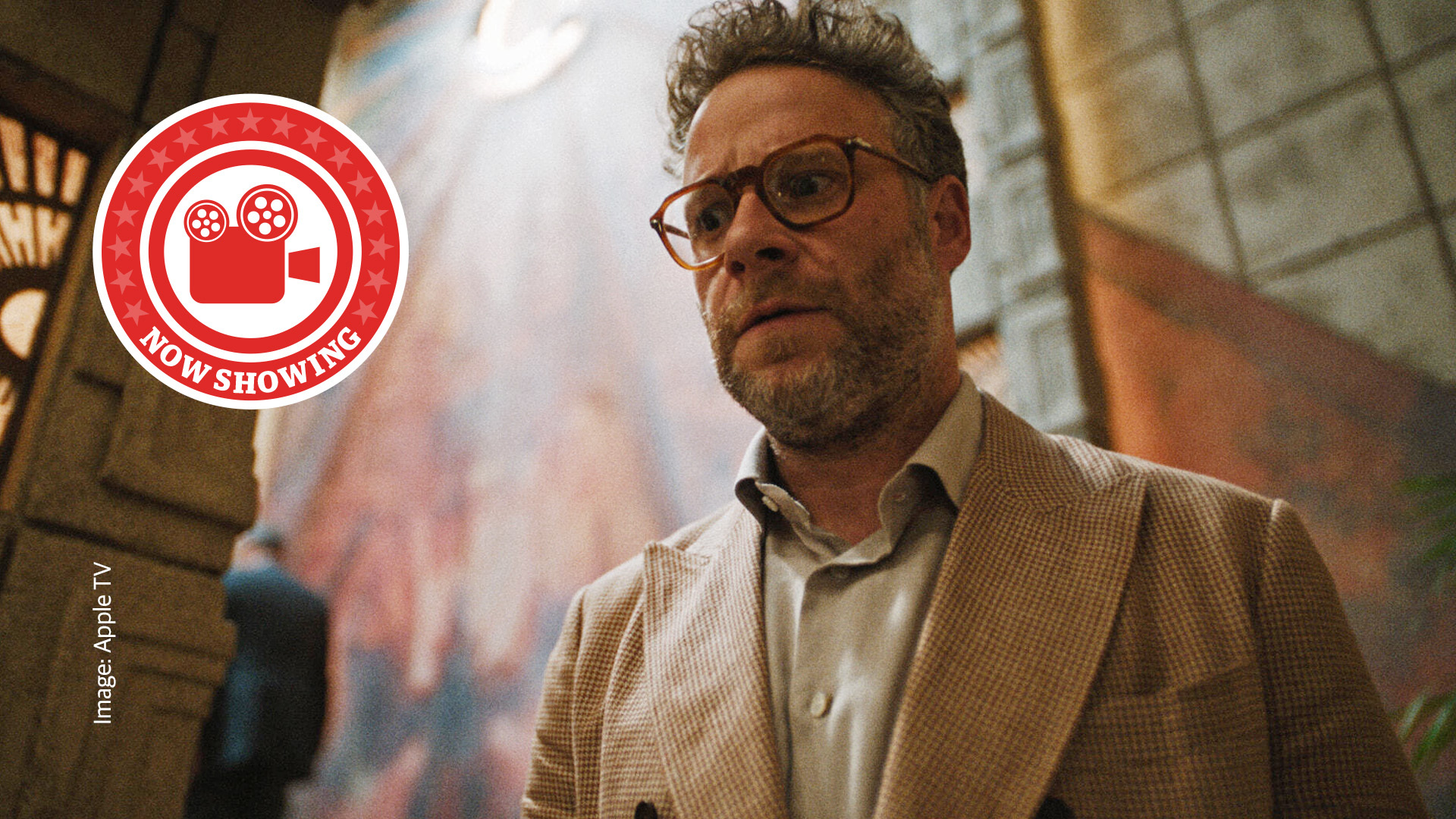 Seth Rogen as Matt Remick from The Studio. He stares off into the distance with a concerned look on his face, wearing a beige suit and brown glasses.