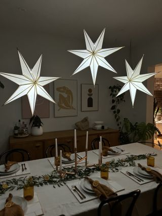 A low lit dining room with paper Christmas lights hanging from the ceiling