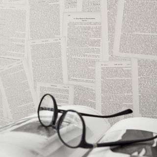 printed wallpaper on wall with spectacles and book