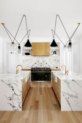 kitchen with marble surfaces and double islands with matching Belfast sinks with contemporary pendant lighting above and range cooker