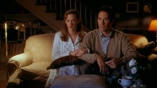 Joan Cusack and Kevin Kline sit together on a couch stunned in In and Out,