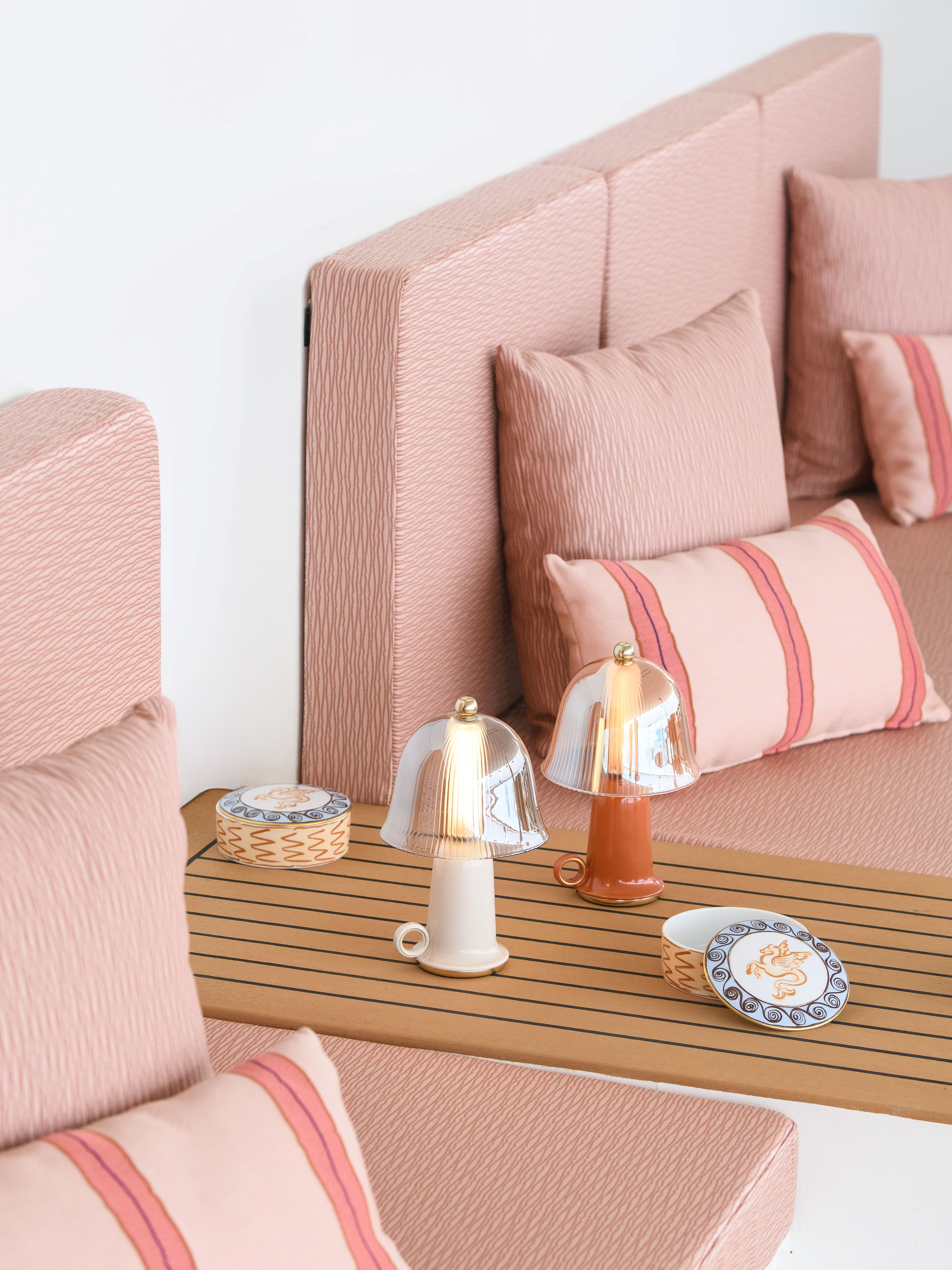 view of a colourful outdoor terrace with pink sunbeds and fine porcelain pieces