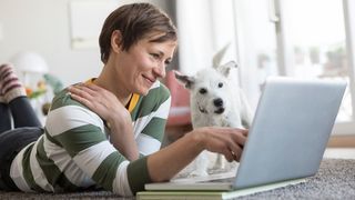 Woman and her dog looking for the best Cyber Monday pet deals at Amazon on a laptop