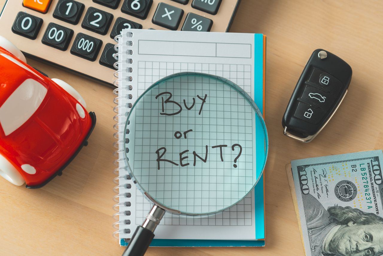 &#039;buy or rent&#039; written on notepad with magnifying glass and various desk items