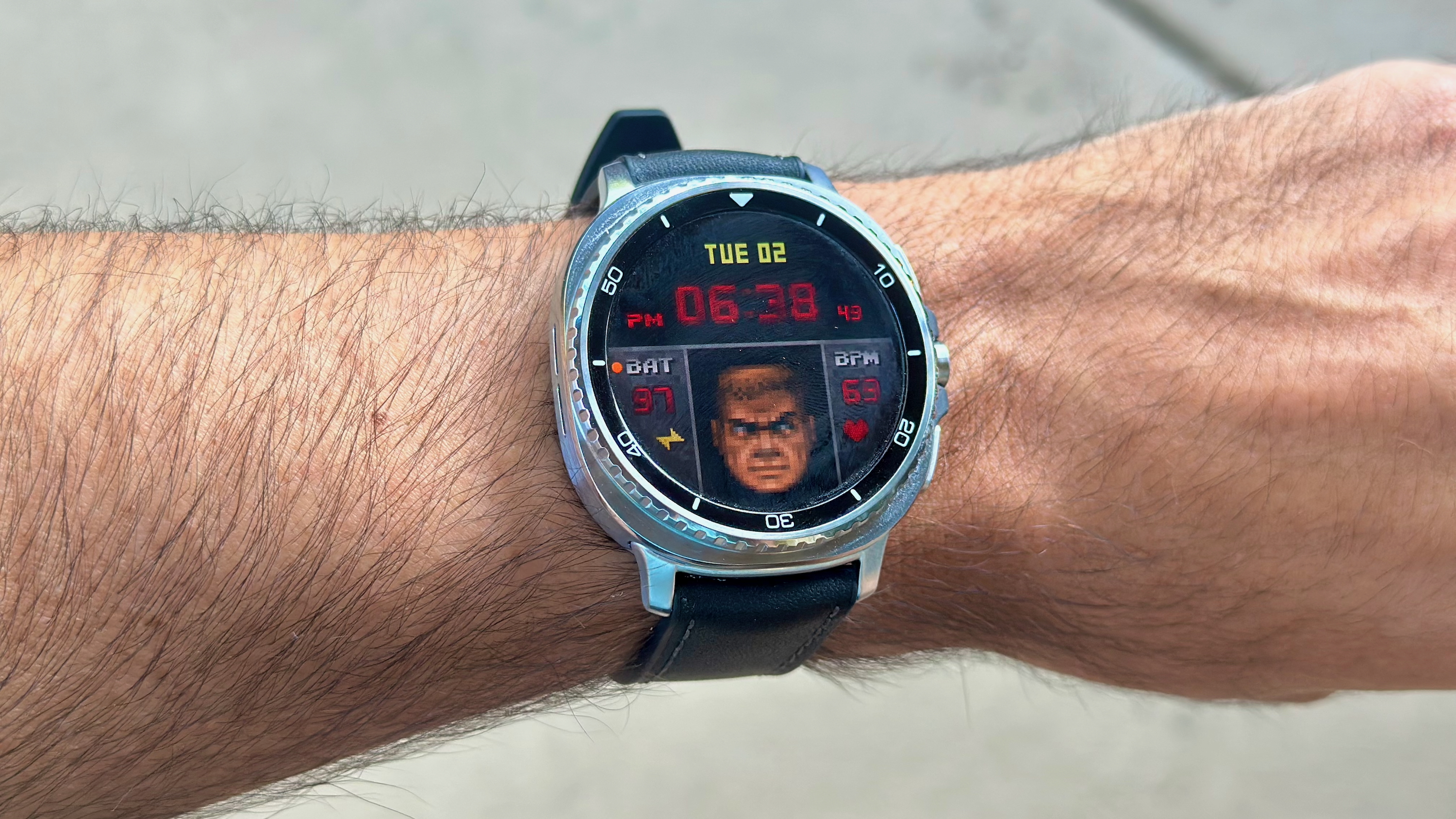 The Samsung Galaxy Watch 8 Classic on a person's wrist, showing a custom watch face from Facer imitating the UI from the classic game Doom.