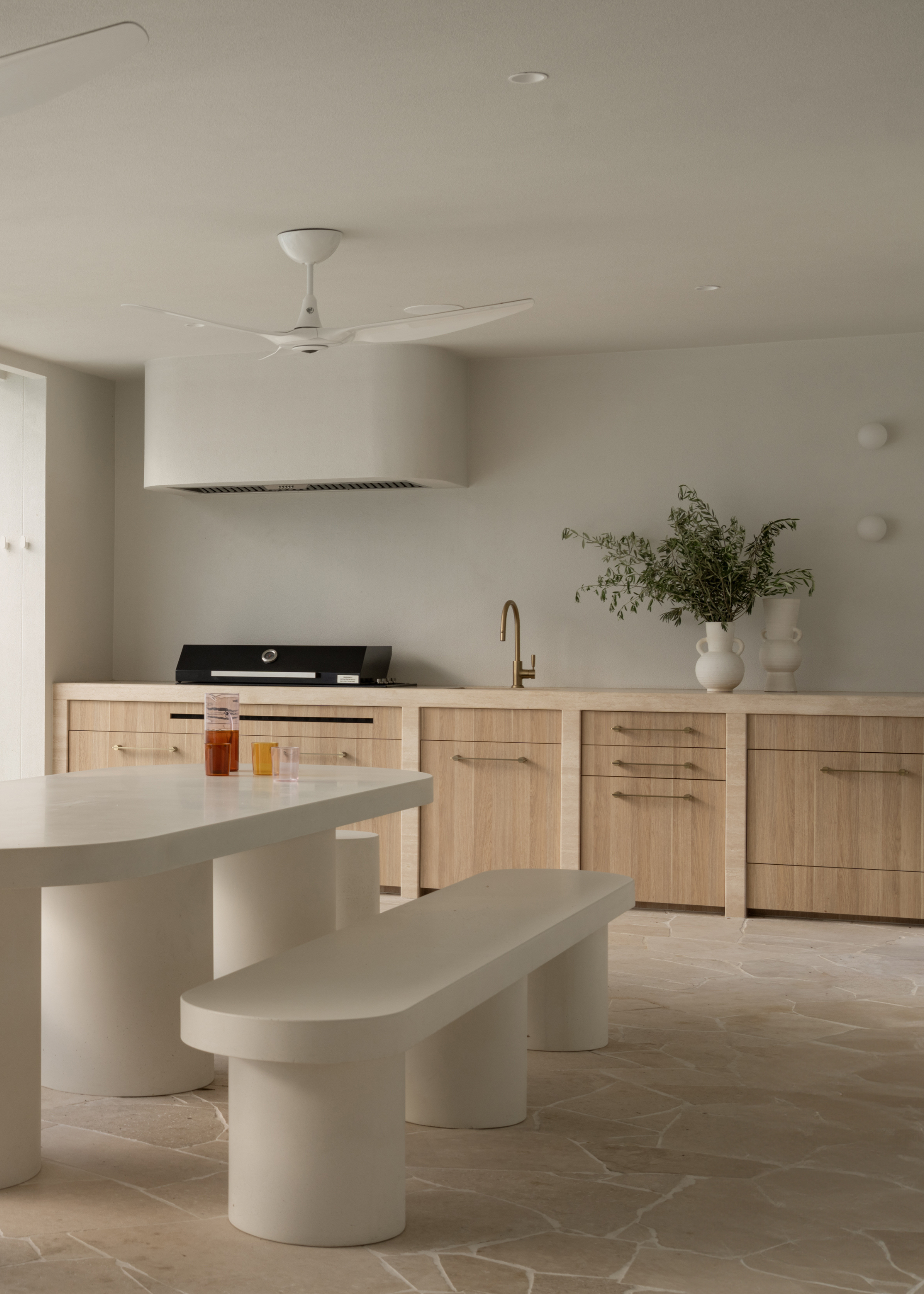 A white kitchen with wooden cabinets, a white dining set, and an in-built exhaust hood