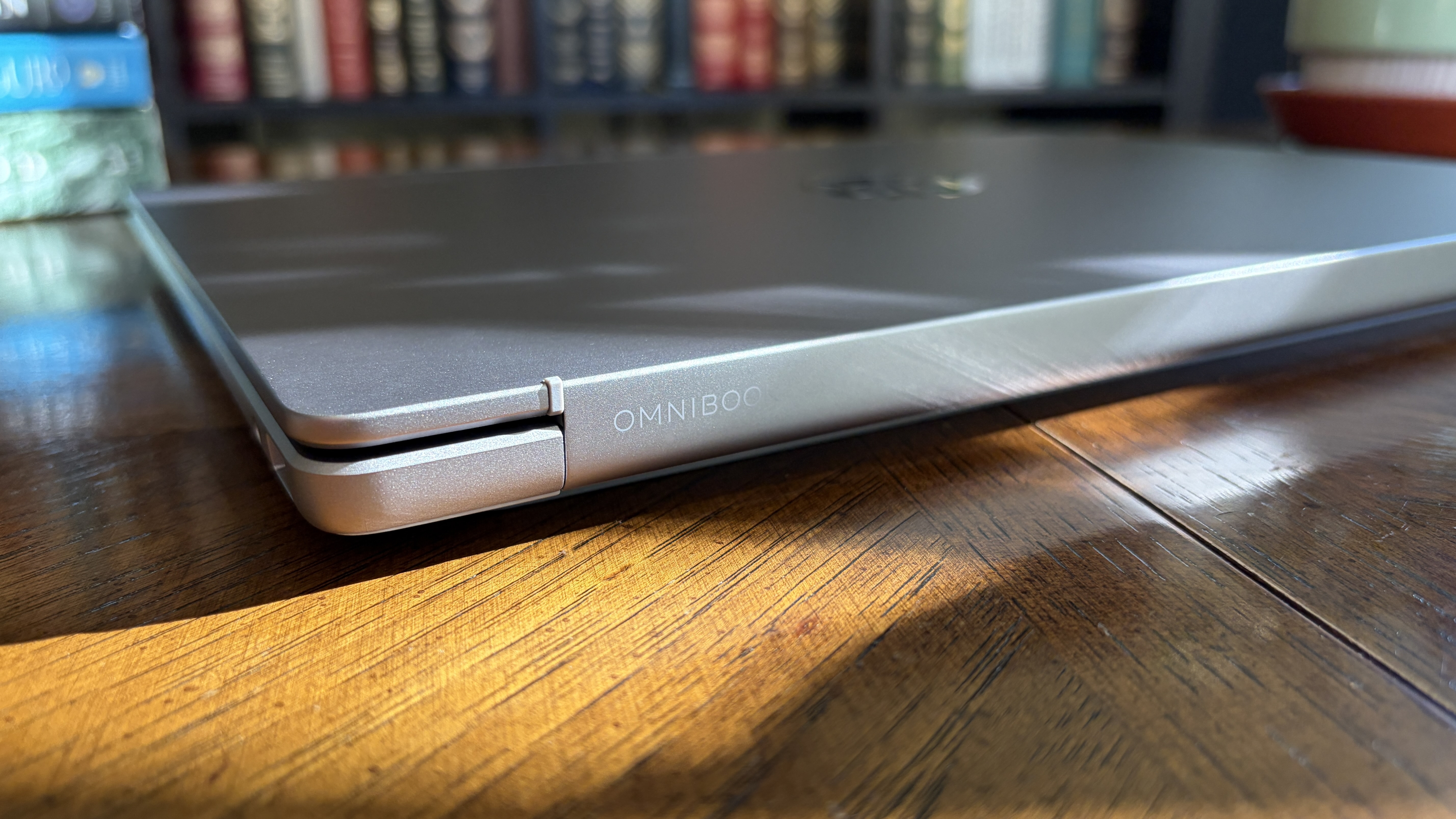A closed laptop on a wooden table, featuring a metallic finish and the brand name "OMNIBOOK" on the side.