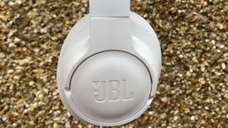A close up of the exterior of one of the cups of the jbl tune 750btnc headphones in white