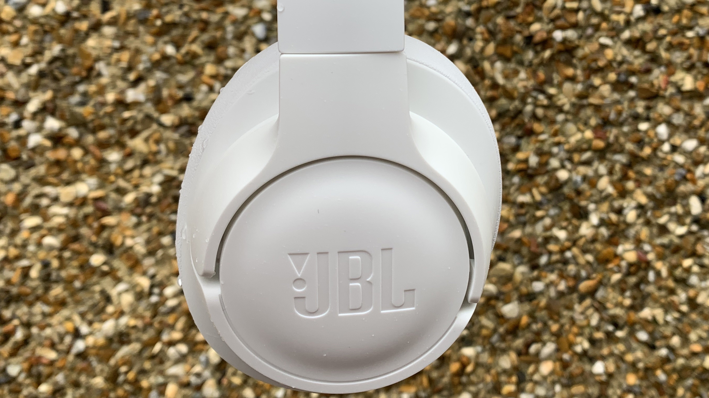 Tampilan dekat bagian luar salah satu cangkir headphone jbl tune 750btnc berwarna putih